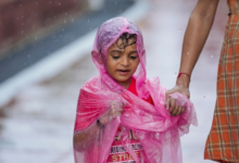 Child covered in a plastic sheet takes a walk during rain at Connaught Place, in New Delhi, Saturday, Aug. 16, 2025. (PTI Photo/Karma Bhutia)