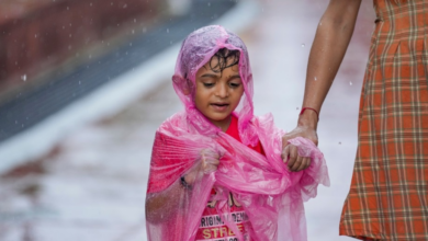 Child covered in a plastic sheet takes a walk during rain at Connaught Place, in New Delhi, Saturday, Aug. 16, 2025. (PTI Photo/Karma Bhutia)